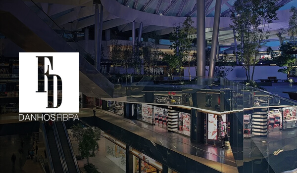 Centro comercial moderno iluminado de noche con logotipo.